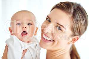 Cute, adorable baby bonding with mother enjoying quality playtime together at home. Proud, loving and happy woman holding her little newborn child while bonding together against a white background