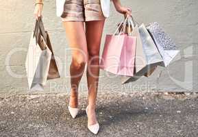 Shopping bags, spending spree or retail therapy for fun, stylish or classy woman buying clothes. Legs of trendy, elegant and sophisticated lady with gifts and presents standing alone on a city street