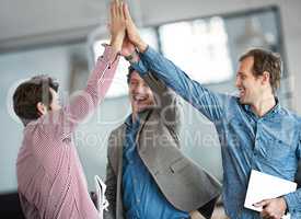 Excited, cheerful and happy group of male business people high fiving for motivation in an office. Group of professional work colleagues show support and celebrating after a team building meeting.