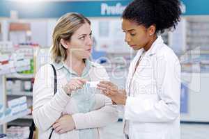 Always prepared to answer all your health questions. a young pharmacist recommending a health care product to a young woman at a pharmacy.