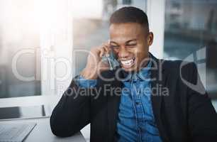 He knows how to handle business over the phone. a handsome young businessman talking on a cellphone while working in an office.