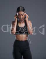 Music can really boost your motivation. Studio shot of a sporty young woman listening to music against a grey background.