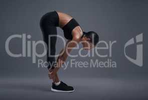 Increasing her flexibility through fitness. Studio shot of a sporty young woman exercising against a grey background.