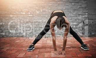 Ill continue stretching towards my goals. a sporty young woman exercising outdoors.