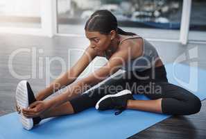 Discipline is every winners secret weapon. an attractive young woman sitting down and doing stretching exercises on her gym mat at home.
