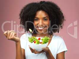 Fuel for the body. Studio shot of an attractive young woman eating salad against a pink background.