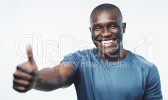 I got you champ, dont worry. Studio shot of a handsome young man posing with his thumb up against a grey background.