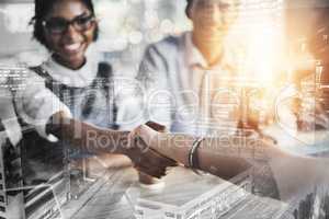 Striking a deal. two young businesspeople shaking hands during a meeting in the boardroom.