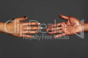 Reaching out for help is an act of strength. Studio shot of two unrecognizable people reaching out their hands towards each other against a grey background.