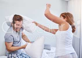 Okay I surrender. a couple having a pillow fight at home.