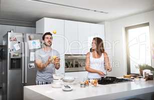 Juggling happiness and love together. a happy young couple preparing breakfast in the morning.