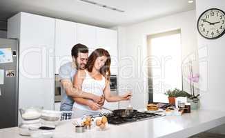 Right in my arms where you belong. a happy young couple preparing breakfast in the morning.