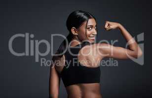 Make fitness an everyday habit. Studio portrait of a young sportswoman flexing her bicep with her back turned to the camera against a gray background.
