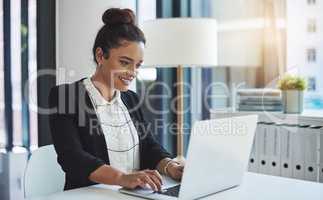 Work hard for the success you want. a young businesswoman using a laptop in a modern office.