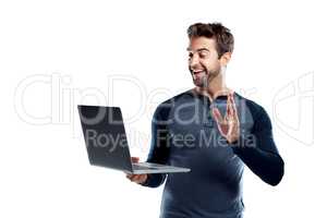 Connect and feel closer than ever. Studio shot of a handsome young man using a laptop and waving against a white background.