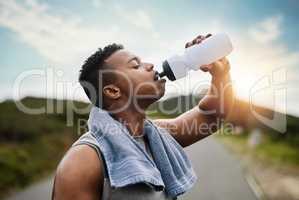 Cooling off after an intense run. a sporty young man drinking water while exercising outdoors.