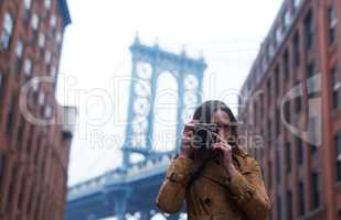 Dont miss out on a single memory. Portrait of an attractive young woman taking pictures with a camera in the city.