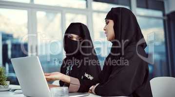 Contributing to the success of their company. two young arabic businesswomen working on a laptop in their office.