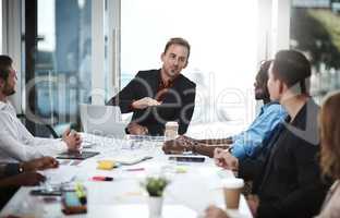 Guiding his team to achieve their best. a businessman having a meeting with his colleagues in a boardroom.
