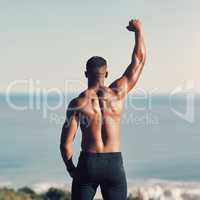 More power to me. Rearview shot of an unrecognizable young man standing with his hand raised while exercising outdoors.