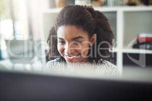 She does everything with a smile on her face. a young businesswoman working on her computer at her desk.