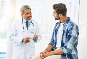 How are you feeling today. a confident mature male doctor consulting with a patient inside of his office during the day.