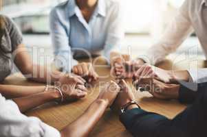 Great things will come from supporting each other. Closeup shot of a group of businesspeople sitting together at a table and holding hands.