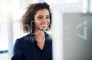 Problem solving makes her smile grow wider. an attractive young female call center agent working in her office.