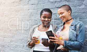 Connect wherever, whenever. two young women standing beside a building smiling and reading through text messages while holding their cool drinks.