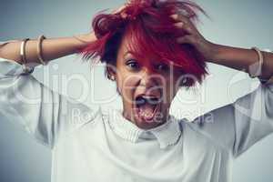 She has fire in her soul. Studio shot of an attractive young woman screaming against a gray background.