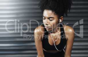 Every workout is worth it in the long-run. a sporty young woman taking a break while exercising against a grey background.