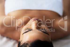 Take a timeout from tension. an attractive young woman relaxing on a massage table at a spa.