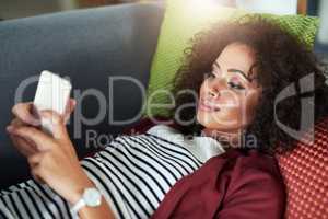 This chill time was much needed. a young woman using a mobile phone while relaxing on the sofa at home.