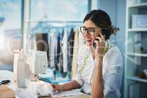 I was just about to call you. an attractive young fashion designer making a phonecall while working in her design studio.