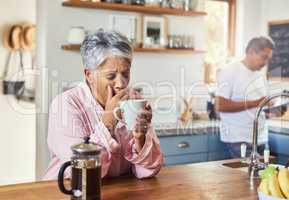 The retired life. a carefree elderly woman sitting at a table in the kitchen drinking coffee and about to sneeze.