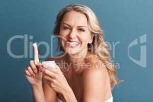 Pampering her skin. Studio portrait of an attractive mature woman applying moisturizer against a grey background.