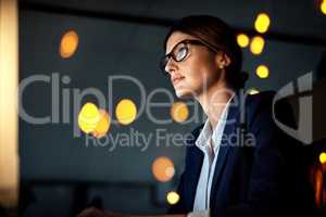 Commitment is key. a young businesswoman working late on a computer in an office.