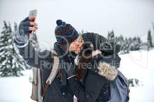Kiss me before your lips freeze. a man taking a selfie with his girlfriend while out on the snow.