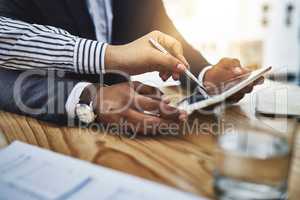 It pays to work smarter. Closeup shot of two businesspeople working together on a digital tablet in an office.