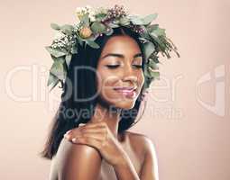 Blissfully natural. Studio shot of a beautiful young woman wearing a wreath while posing with her eyes closed against a pink background.