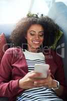 Connect with good company. a young woman using a mobile phone while relaxing on the sofa at home.