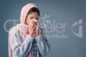 Shes got the sniffles. Studio shot of an attractive young woman blowing her nose while standing against a grey background.