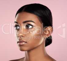 This perfect skin tone takes work. Studio shot of a beautiful young woman posing with moisturizer on her face against a pink background.