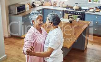 Just like we first met. a carefree elderly couple having a dance inside of the kitchen at home during the day.