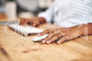 Hand on a mouse, clicking and scrolling while browsing online and surfing the internet. Closeup of a woman using a computer while sitting at a wooden desk. Connect with wireless bluetooth technology