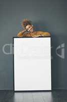 A beautiful confident woman holding a blank whiteboard or billboard sign with copy space. Happy and attractive female with a smile standing behind a banner. Young lady advertising with a poster