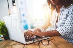 Hands of a woman working with her laptop on a wooden table indoors. Closeup of entrepreneur typing in an open plan home office. Female blog writer brainstorming new creative ideas.