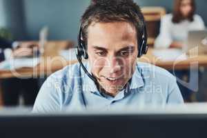 Closeup of a young male call center agent consulting and giving support while working in a busy office. Face of a man and helpdesk worker or phone operator having a conversation