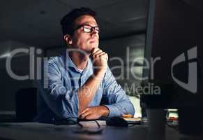 Businessman thinking of ideas in front of a computer while working late in an office at night. Hard Working entrepreneur sending emails, online research and reports trying to reach deadline overtime