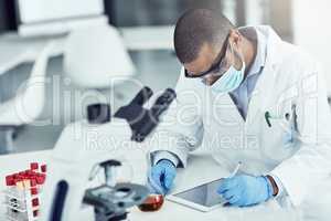 Scientist, researcher and medical worker using a tablet for innovation and research while wearing a face mask in a lab. Male chemist working to find a cure for covid virus in a science facility